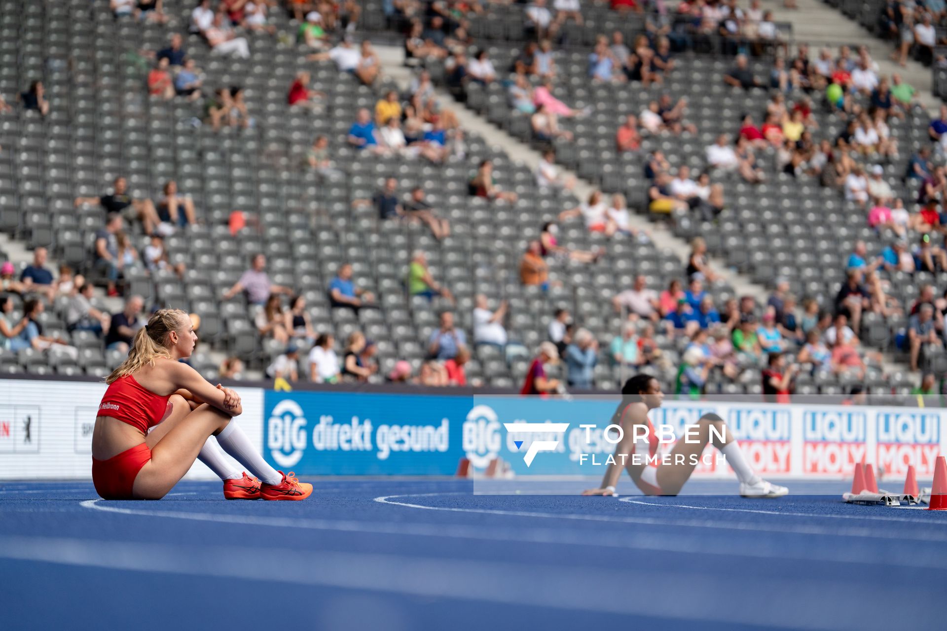 Jara Ellinger (TSG 1845 Heilbronn) und Blessing Enatoh (TSV Spandau 1860) sitzen auf der Bahn waehrend der deutschen Leichtathletik-Meisterschaften im Olympiastadion am 25.06.2022 in Berlin